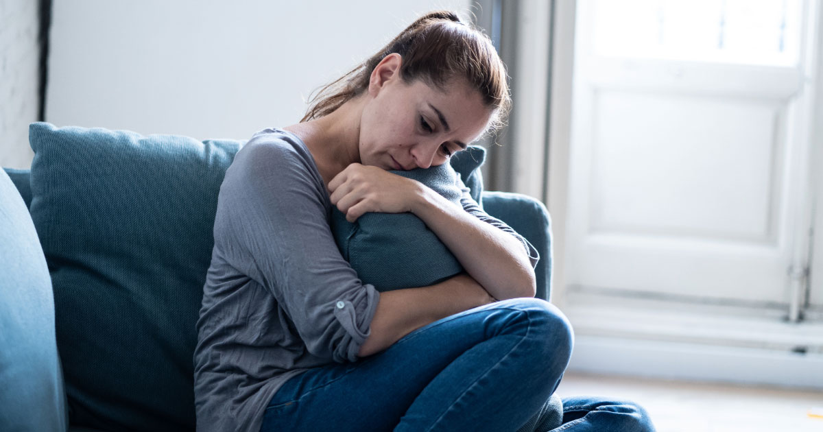 Woman holding pillow while sitting on couch