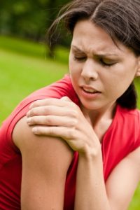 Young woman grabbing her arm with shoulder pain